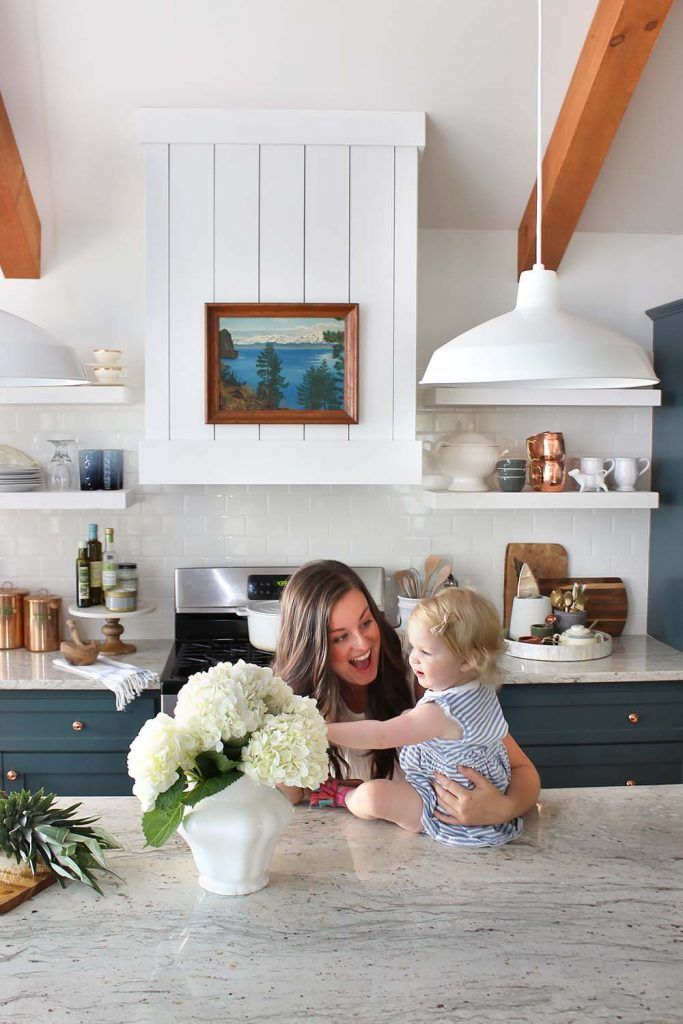 a woman and her child are in the kitchen with flowers on the counter top next to the sink