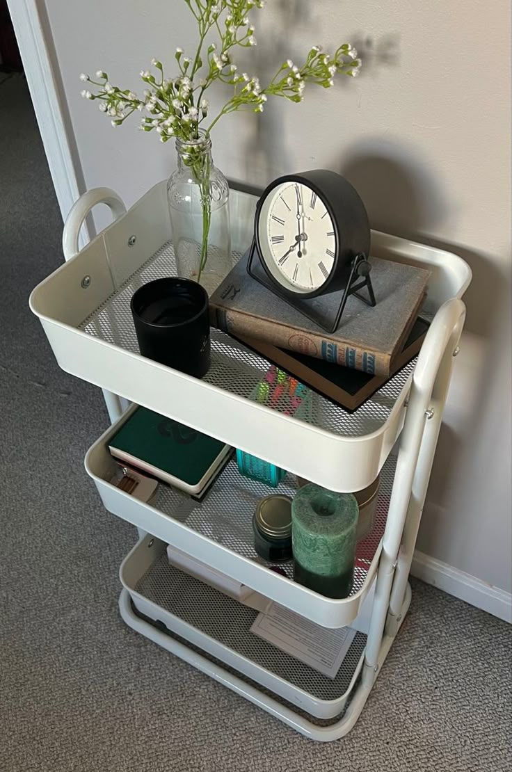 a table with books and a clock on it next to a vase filled with flowers