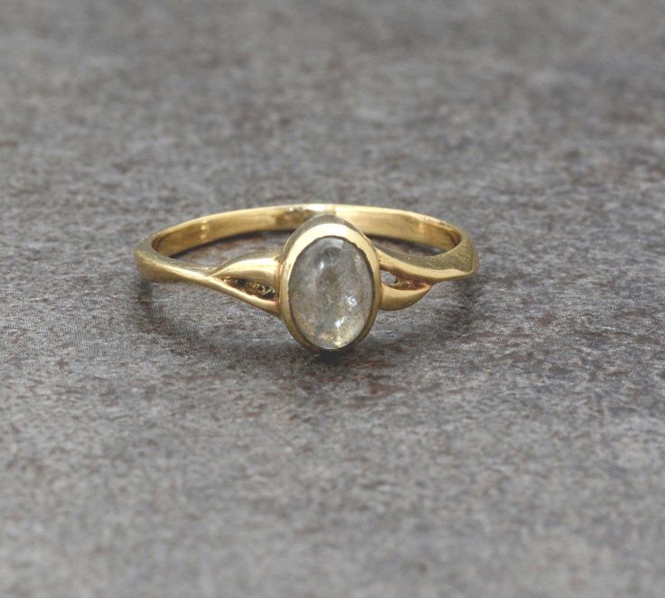 a yellow gold ring with a white diamond in the center on a gray surface,