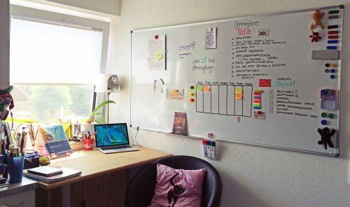 a desk with a laptop computer sitting on top of it next to a whiteboard