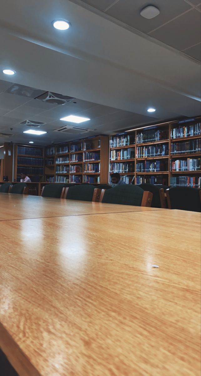 an empty conference room with wooden tables and bookshelves