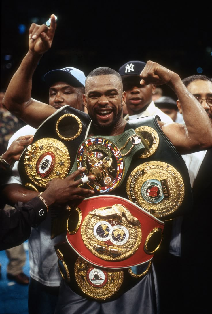 the professional boxer is holding his belt in front of other men as he stands next to him