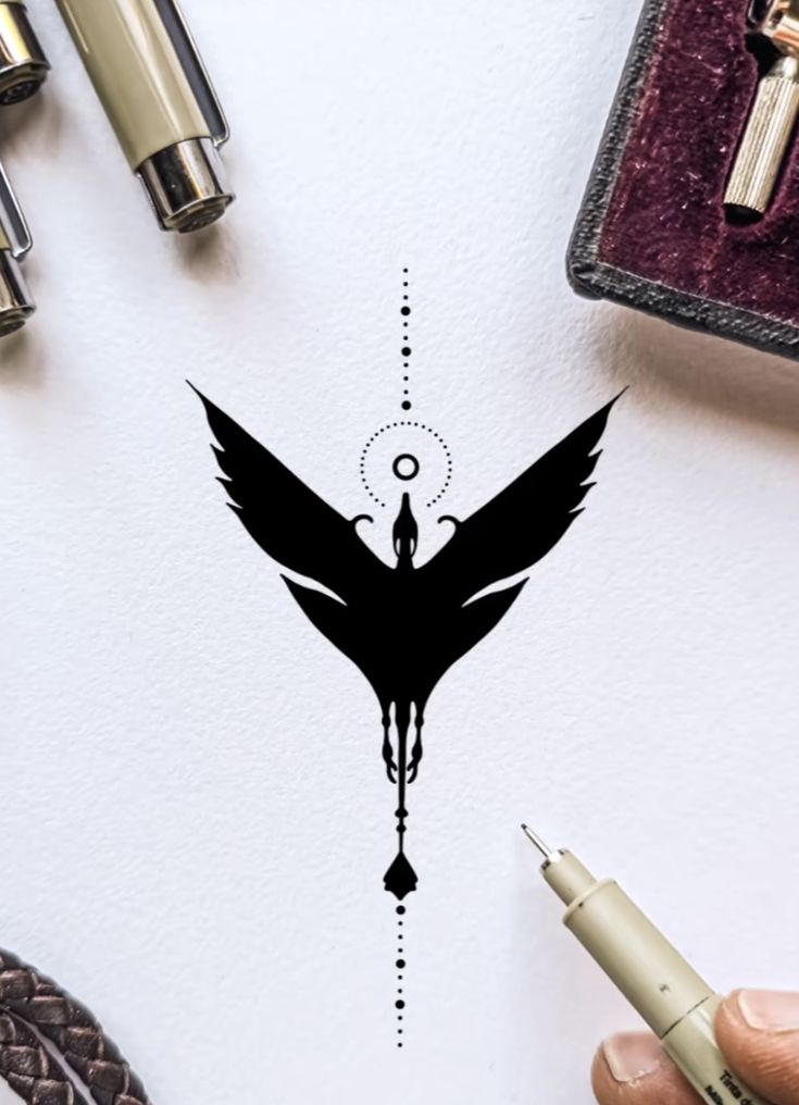 a drawing of a black bird on top of a white paper next to some pens