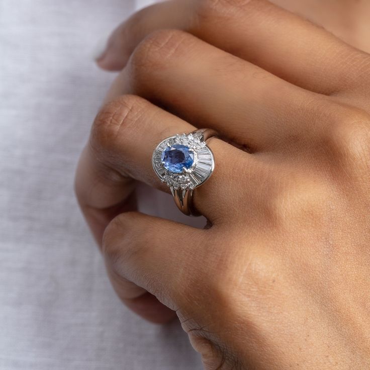 a close up of a person's hand holding a ring with a blue stone