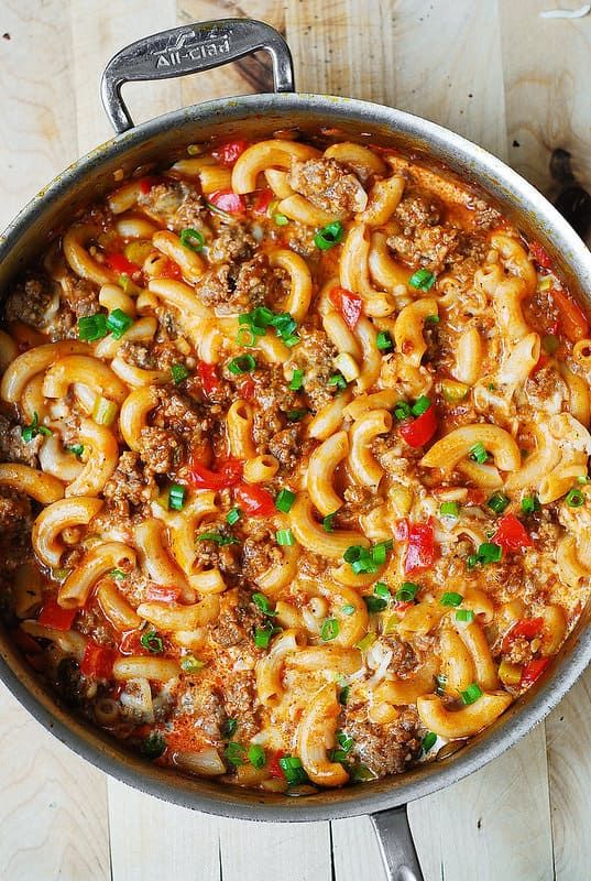 a pot filled with pasta and meat on top of a wooden table