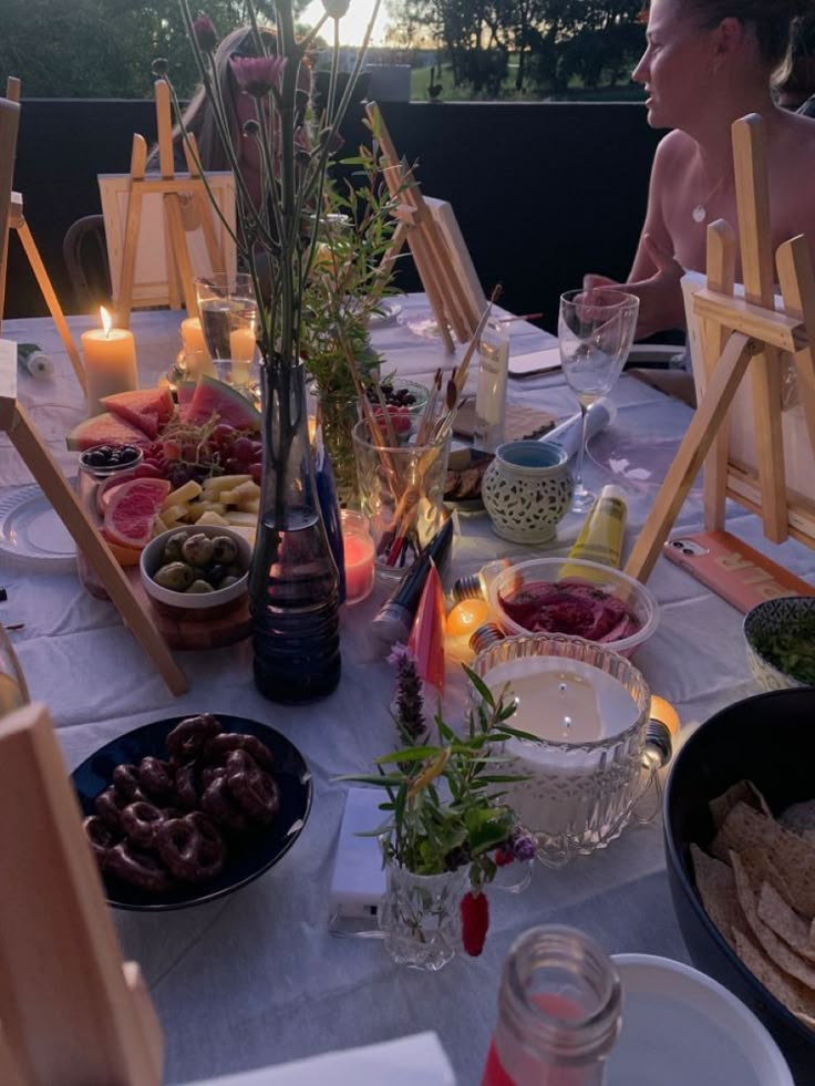 the table is set with food and candles for an outdoor dinner or party in the evening