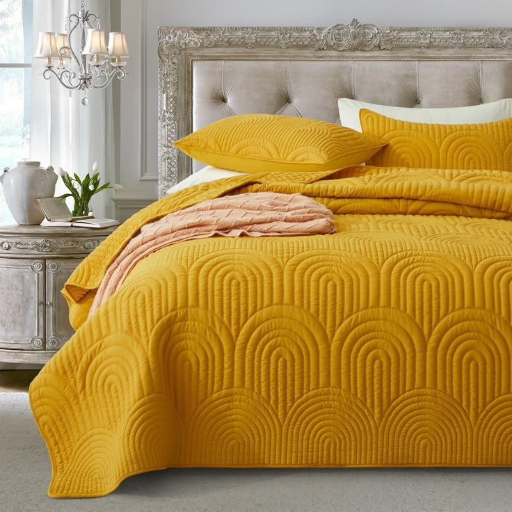 a bed with yellow comforters and pillows in a bedroom setting that looks like art deco