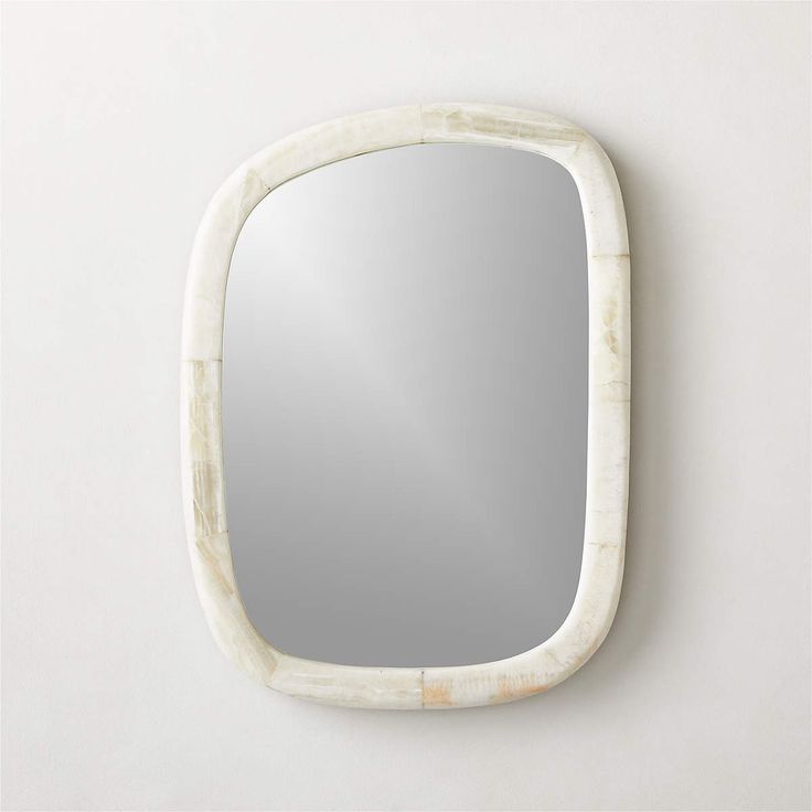 a mirror that is on the wall next to a white wall with a marble frame