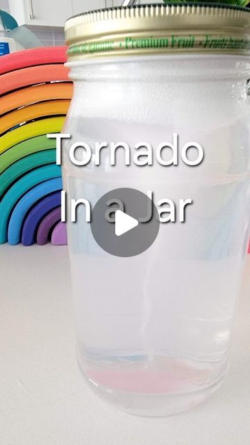 a glass jar filled with liquid sitting on top of a table next to rainbow colored plates