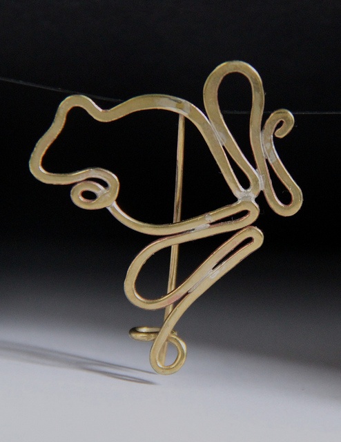 a gold brooch with an animal on it's back and the word love spelled in cursive writing