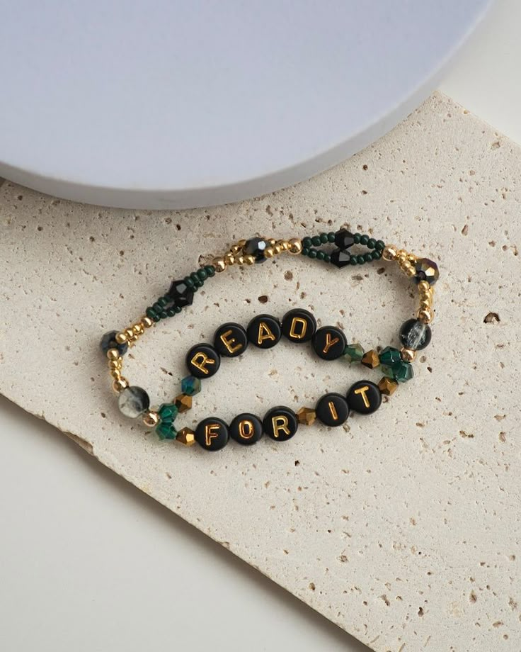 two beaded bracelets sitting on top of a white plate