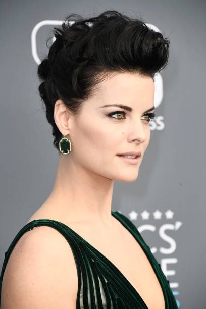 a woman with black hair and green dress on the red carpet at an awards event