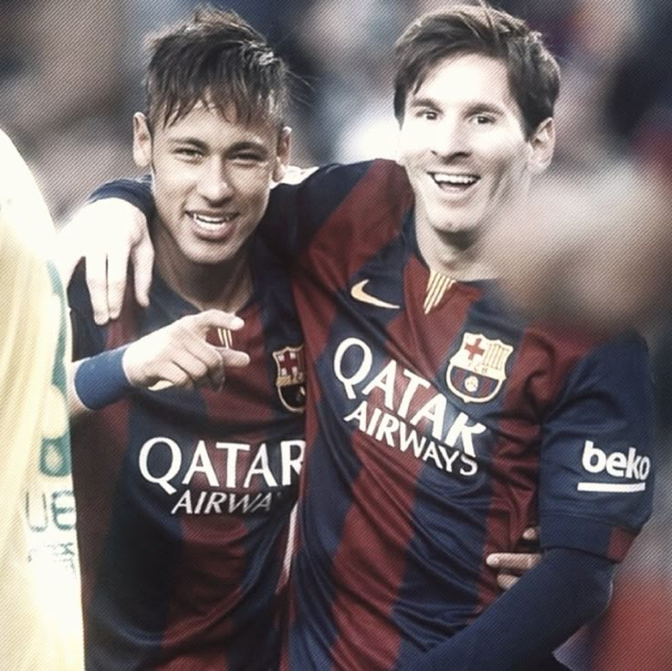 two young men standing next to each other on a soccer field