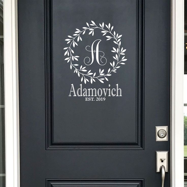 the front door is painted black and has a monogrammed wreath with initials on it