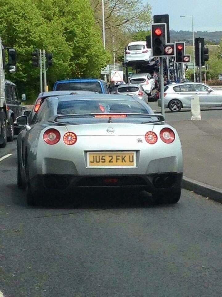 a silver sports car driving down a street next to traffic lights and cars parked on the side of the road