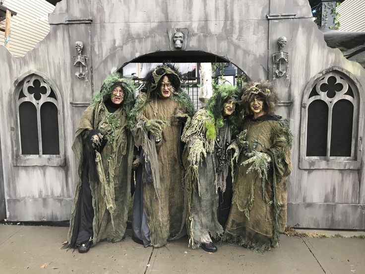 three people dressed up as witches standing in front of a building