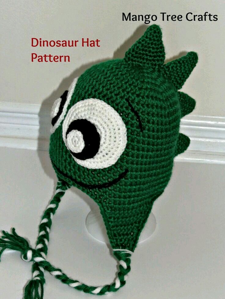 a green crocheted hat with eyes on the front and side, attached to a hook