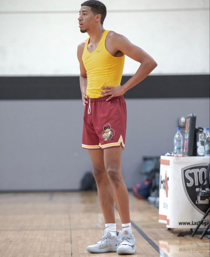 a man standing on a basketball court with his hands on his hips and looking to the side