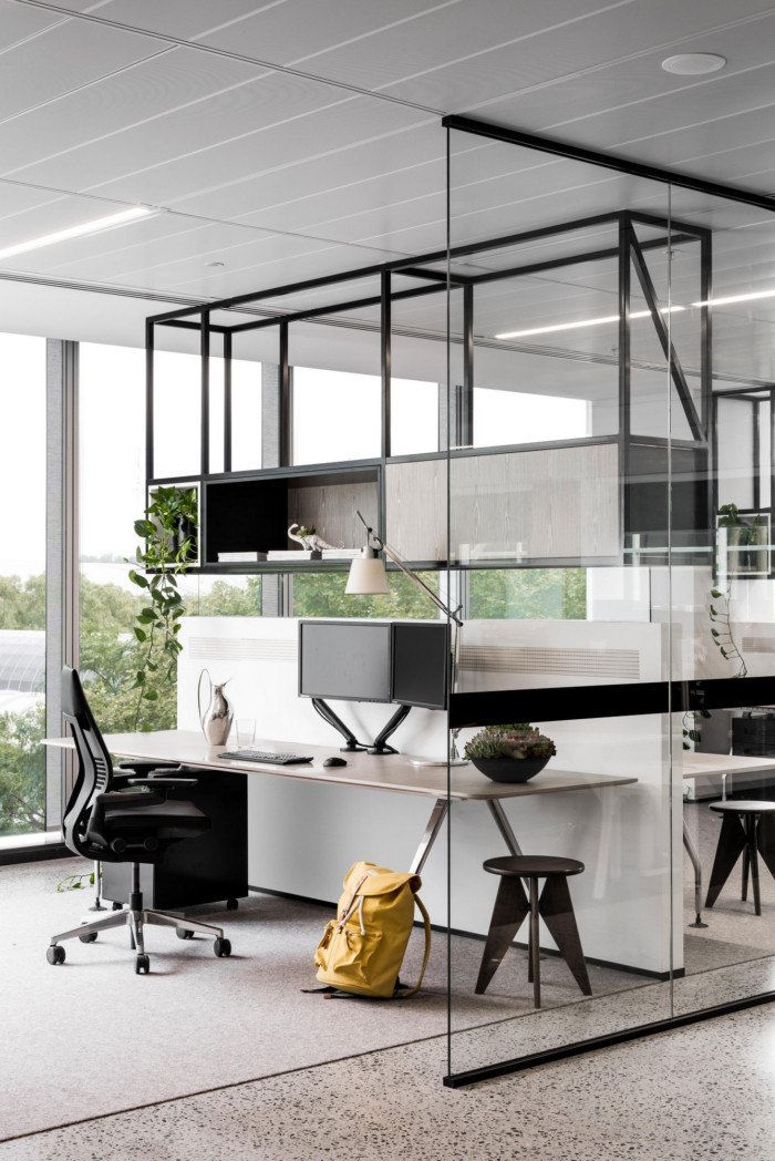 an office with glass walls and desks in the center, along with two chairs