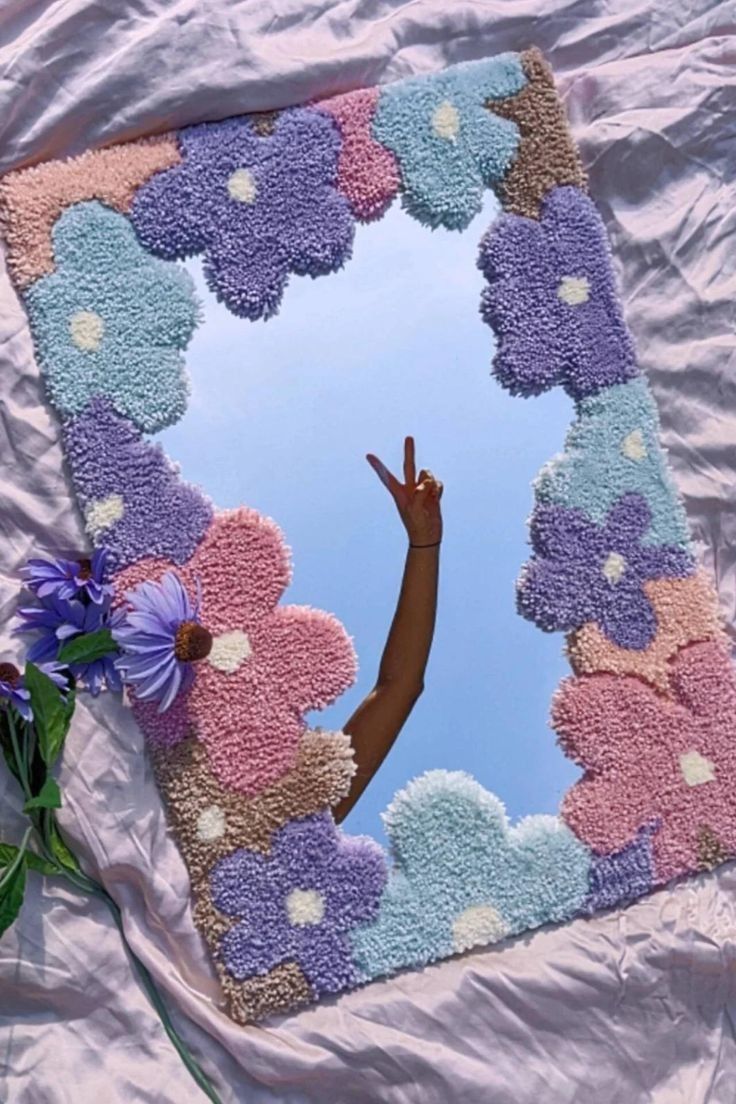 a person reaching up into the sky through a flowered frame on a bed sheet