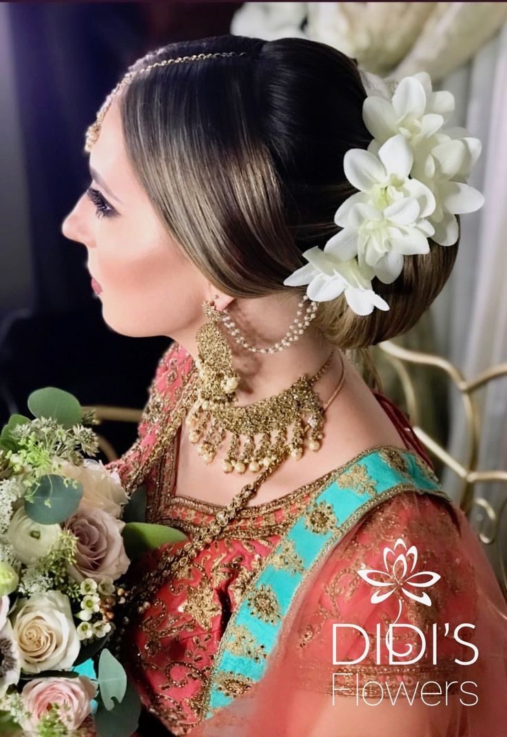 a woman with flowers in her hair wearing a bridal outfit and holding a bouquet