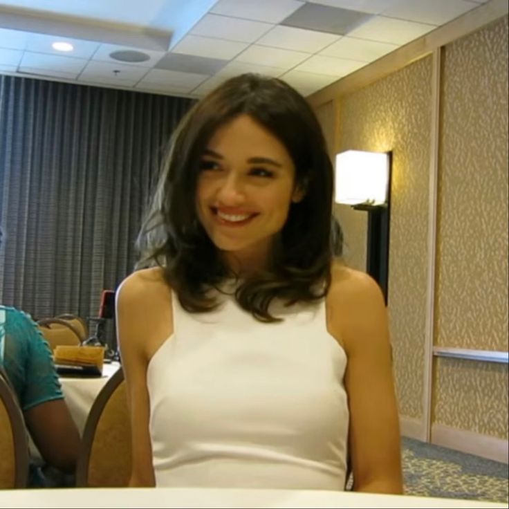 a woman sitting at a table smiling for the camera