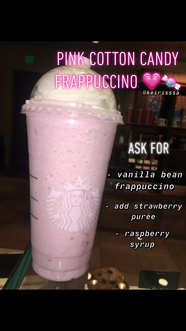 a pink cotton candy frappuccino drink with whipped cream on top and cookies in the background