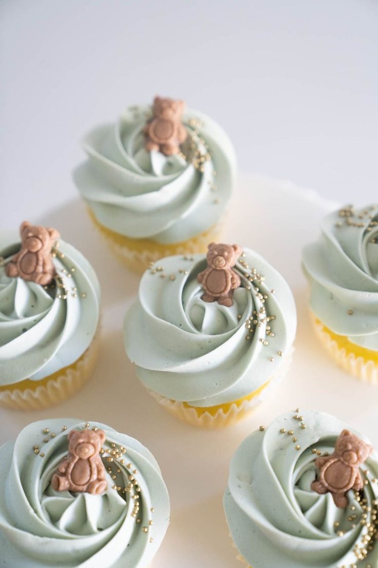 several cupcakes with frosting and teddy bears on them sitting on a plate