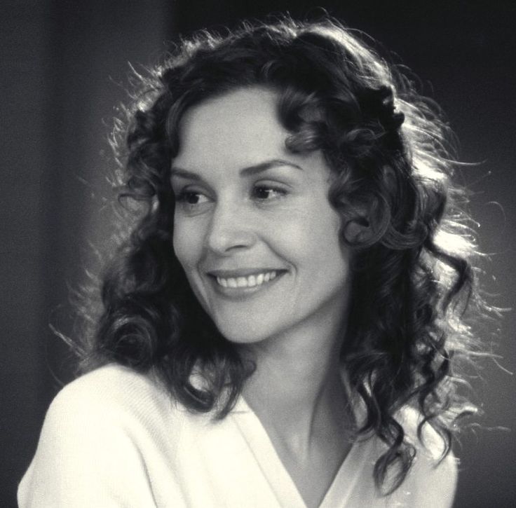 a black and white photo of a woman with curly hair wearing a robe smiling at the camera