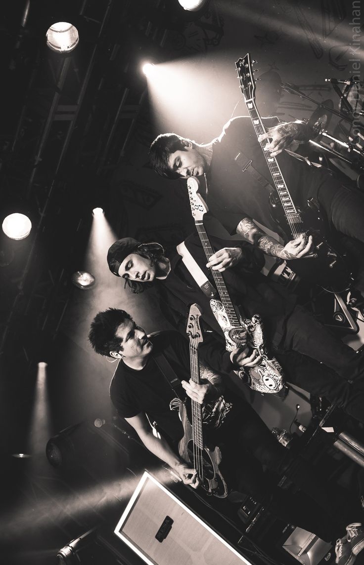 three men are playing guitars on stage