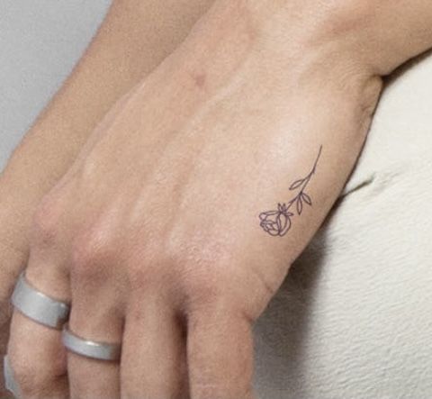 a woman's hand with a small flower tattoo on her left wrist and ring