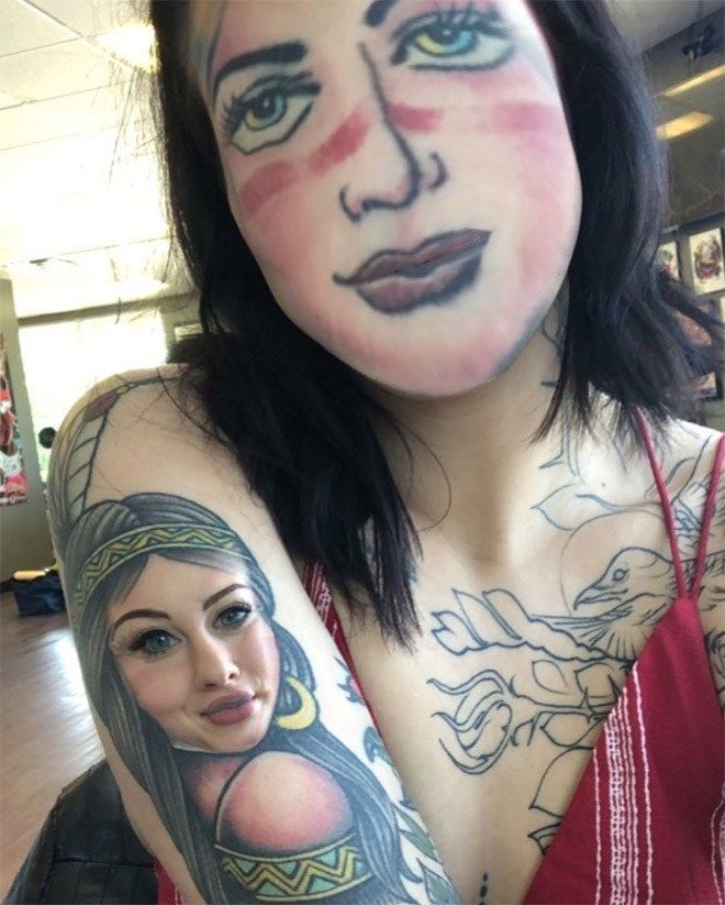 a woman with tattoos on her face and arm is holding a cell phone in front of her face