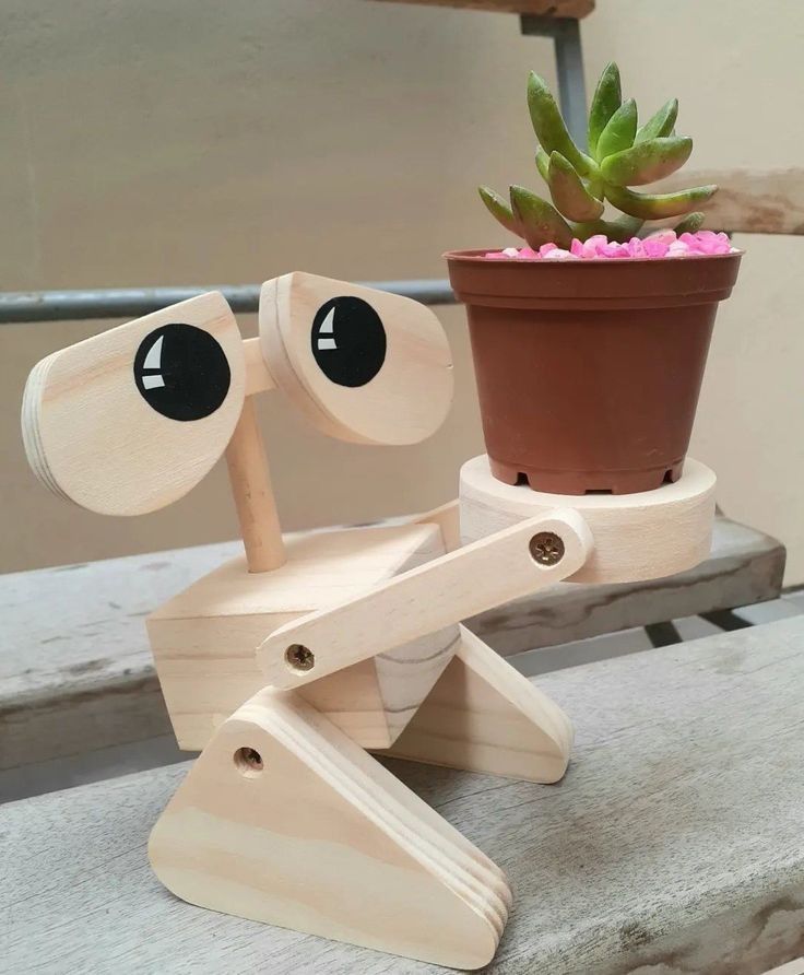 a wooden toy sitting on top of a table next to a potted plant with eyes