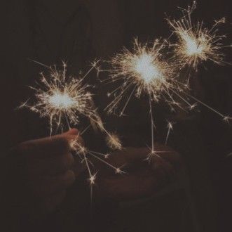 someone holding out their hand with two sparklers in the air and one is pointing at it