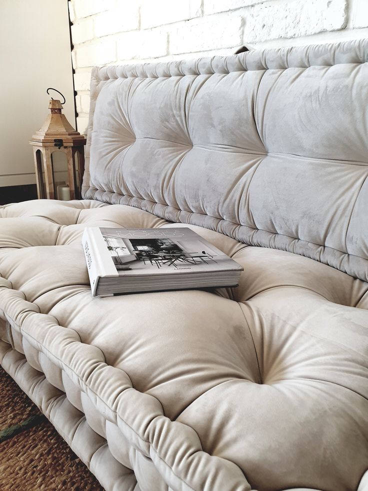 a book sitting on top of a couch in front of a brick wall and lamp