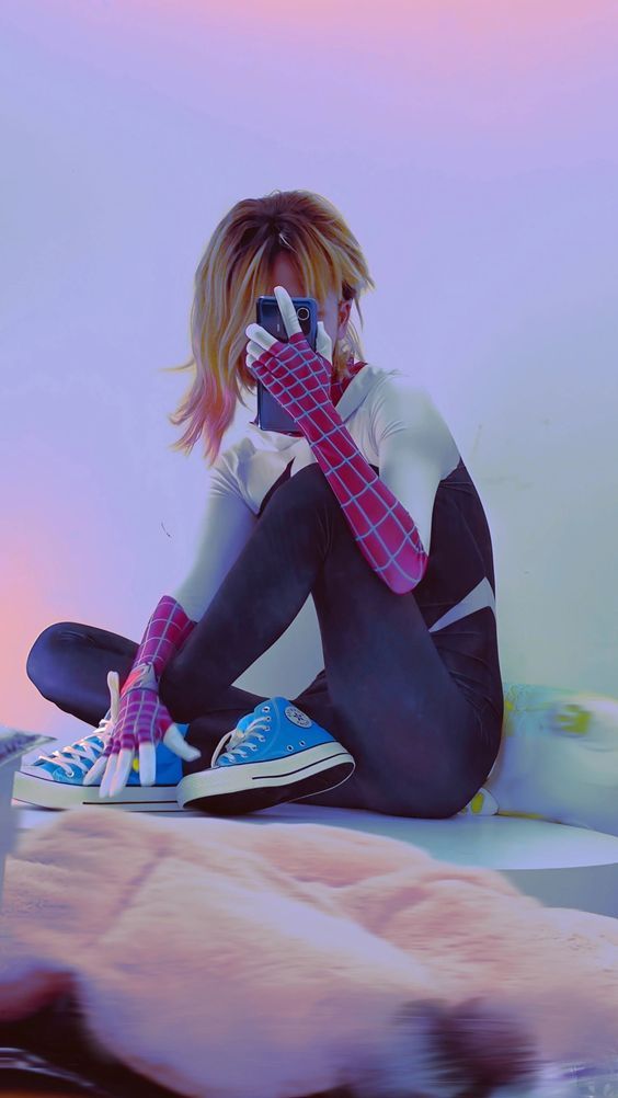 a woman sitting on top of a bed with her hands covering her face and wearing blue sneakers