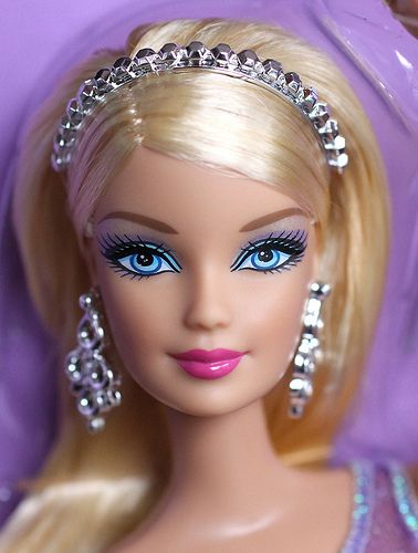 a barbie doll with blue eyes wearing a tiara and diamond jewelry on her head