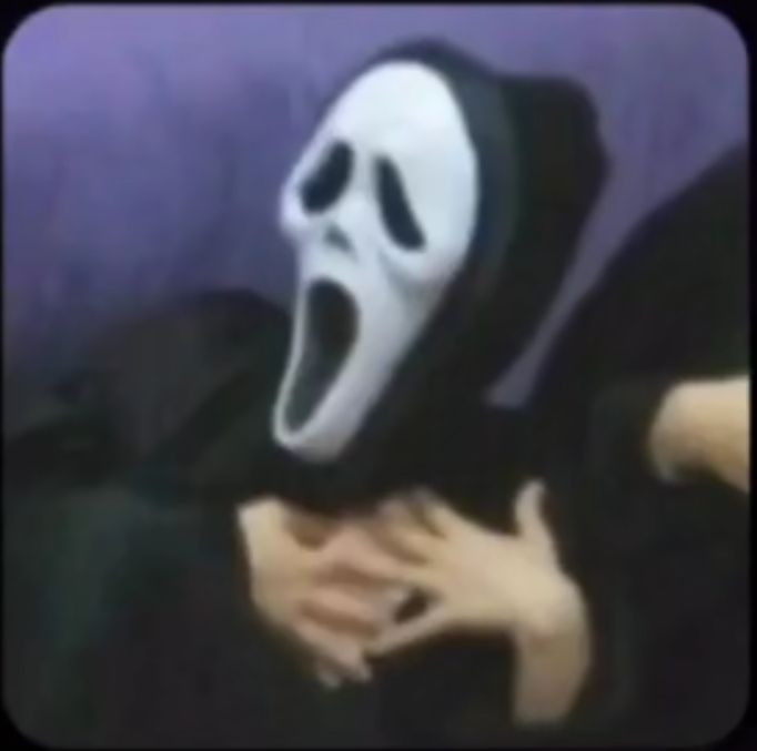 a person wearing a ghost mask laying on a couch