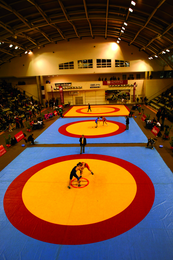 an indoor wrestling match with two wrestlers on the rings