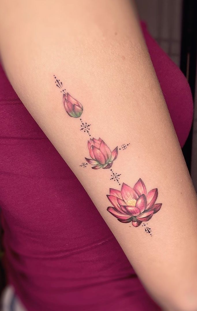 a woman's arm with three pink flowers tattooed on the left side of her arm