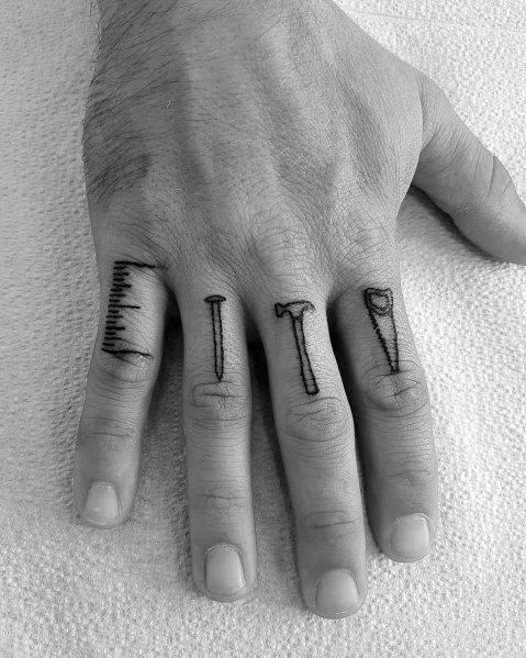 two fingers with small tattoos on them, one has a cross and the other has a letter