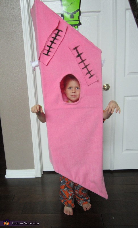 a child wearing a pink house costume standing in front of a white door with a green monster on it's head