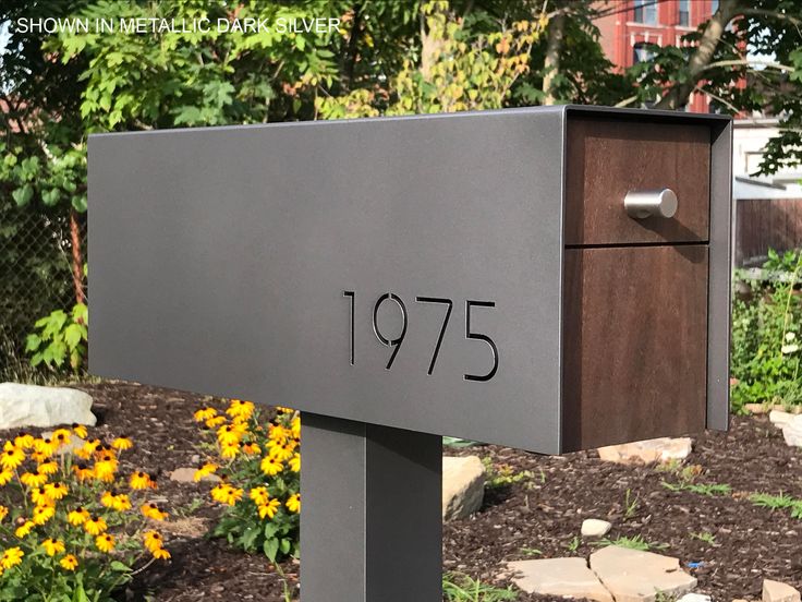 a mailbox with the number seventy five on it in front of some yellow flowers