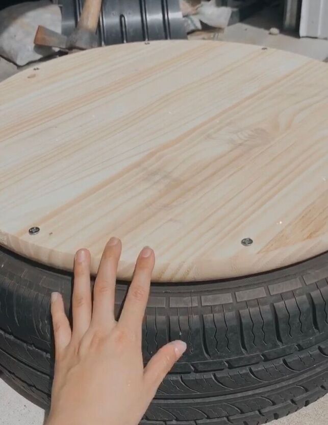 a person's hand is touching the top of a wooden table that has been made from an old tire