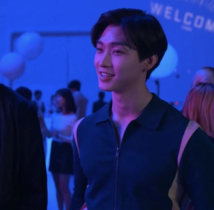 a young man standing in front of a blue wall with balloons on it's sides