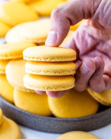 a person picking up some yellow cookies from a pan