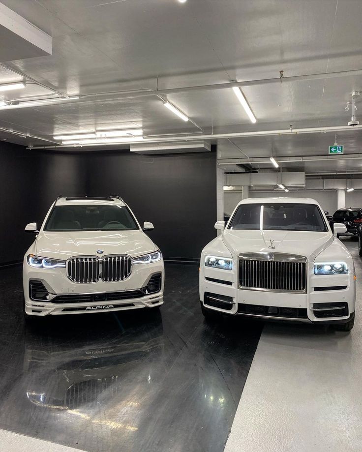 two white cars parked in a parking garage next to each other on black and white flooring