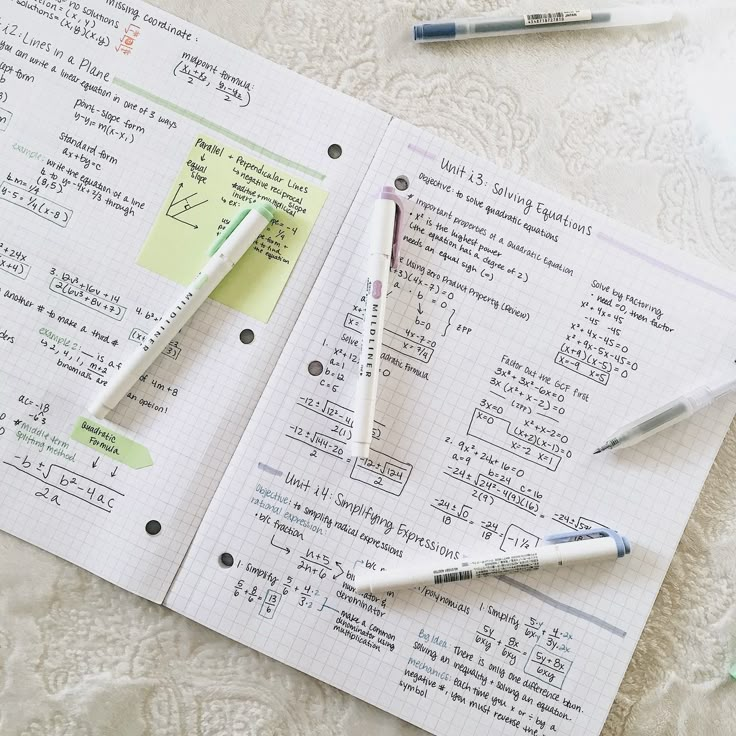 two pens sitting on top of a piece of paper next to some writing utensils