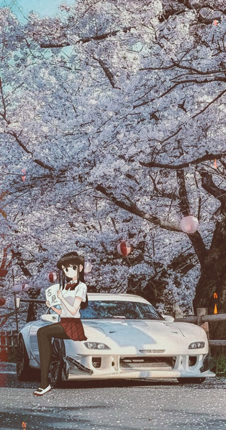 a woman sitting on the hood of a sports car in front of cherry blossom trees