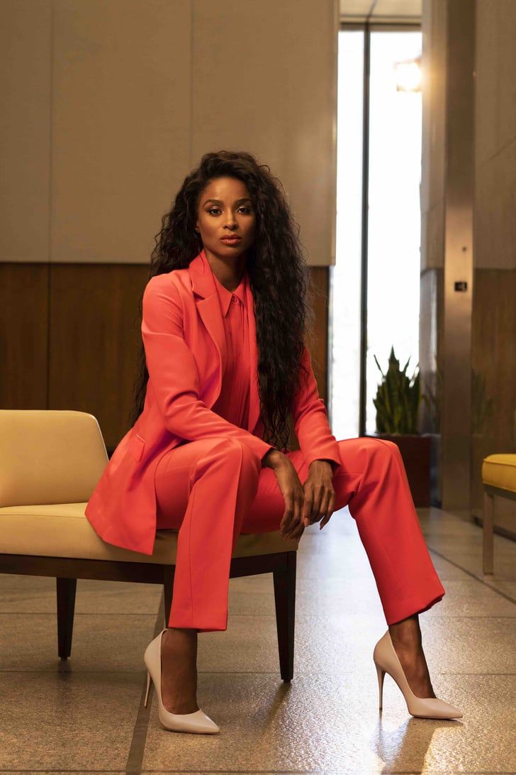 a woman in an orange suit sitting on a bench with her legs crossed and feet crossed